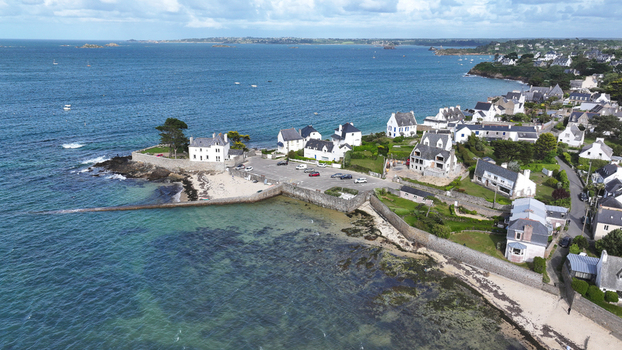 Aerial view of the coastal town of Carantec featuring white houses with slate roofs a stone sea wall and the turquoise waters of the English Channel Carantec Brittany France. Aerial view of the coastal town of Carantec featuring white houses with slate roofs a stone sea wall and the turquoise waters of the English Channel Carantec Brittany France.