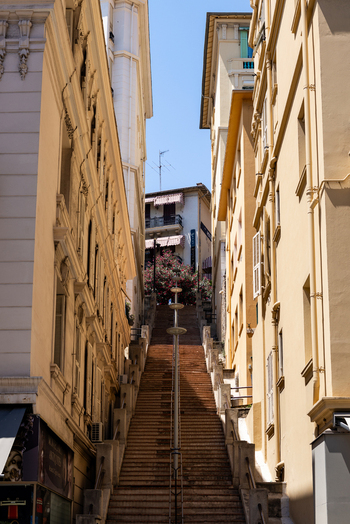 View of a narrow street with a long staircase flanked by tall yellow buildings under a clear blue sky in Monaco City Monaco. View of a narrow street with a long staircase flanked by tall yellow buildings under a clear blue sky in Monaco City Monaco.