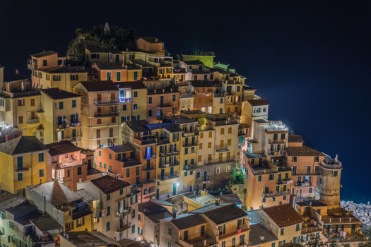 View of the colorful houses of Manarola illuminated at night on the cliffside of the Cinque Terre coast in Manarola Liguria Italy. View of the colorful houses of Manarola illuminated at night on the cliffside of the Cinque Terre coast in Manarola Liguria Italy.
