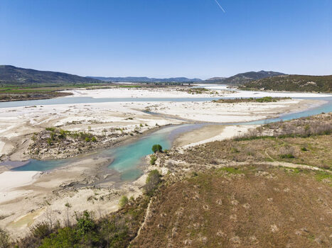 Aerial view of Vjosa Wild River National Park featuring turquoise river channels expansive white gravel bars and surrounding hills in Permet Gjirokaster County Albania. Aerial view of Vjosa Wild River National Park featuring turquoise river channels expansive white gravel bars and surrounding hills in Permet Gjirokaster County Albania.