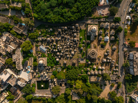 Aerial view of the historic Ahar Cenotaphs featuring numerous stone domes and intricate architectural details surrounded by lush green trees in Udaipur Rajasthan India.