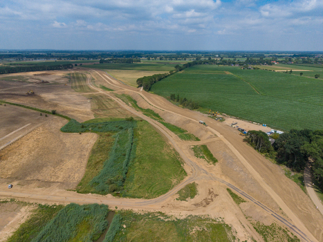 Aerial view of a land development project with dirt roads green fields and construction equipment in the Netherlands. Aerial view of a land development project with dirt roads green fields and construction equipment in the Netherlands.