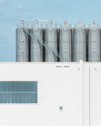 Aerial view of storage hub with rows of tall stainless steel silos and a modern white industrial building under a clear blue sky in Kutno Lodzkie Poland. Aerial view of storage hub with rows of tall stainless steel silos and a modern white industrial building under a clear blue sky in Kutno Lodzkie Poland.