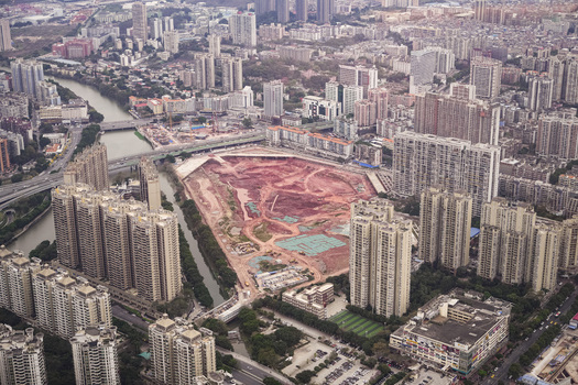 Aerial view of a large urban construction site surrounded by high rise residential buildings and a river in Guangzhou Guangdong Province China. Aerial view of a large urban construction site surrounded by high rise residential buildings and a river in Guangzhou Guangdong Province China.