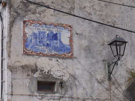 View of a blue and white tile mural depicting the historic Paco de Flor da Rosa castle on a weathered stone wall with a vintage street lamp in Portalegre Portalegre District Portugal.