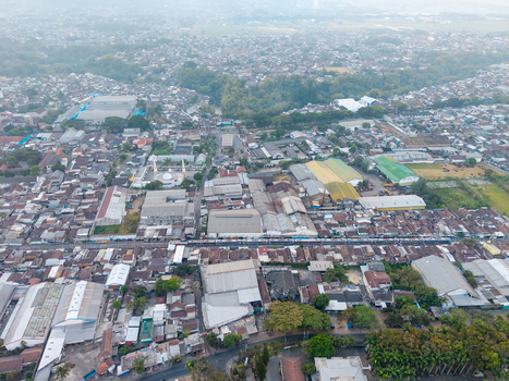Malang East Java Indonesia 23 August 2026 Aerial view of the city of Malang showing dense urban housing industrial buildings a railway line and surrounding greenery.