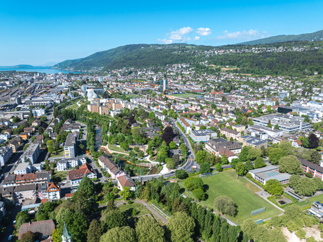 Aerial view of the urban landscape of Biel Bienne featuring residential areas lush green parks and industrial zones against the backdrop of the Jura mountains Biel Bienne Canton of Bern Switzerland.