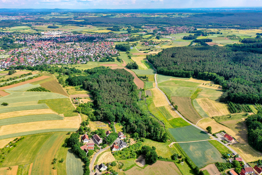 Aerial view of the town of Neunkirchen am Brand surrounded by lush green forests and colorful agricultural fields under a clear sky Neunkirchen am Brand Bavaria Germany. Aerial view of the town of Neunkirchen am Brand surrounded by lush green forests and colorful agricultural fields under a clear sky Neunkirchen am Brand Bavaria Germany.