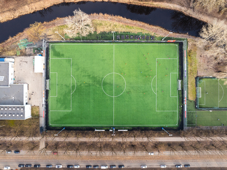 Aerial view of a soccer field with players on artificial turf surrounded by trees and a canal in Riga Latvia. Aerial view of a soccer field with players on artificial turf surrounded by trees and a canal in Riga Latvia.