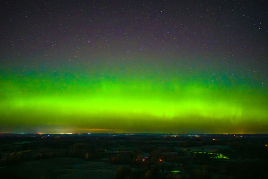 Aerial view of the vibrant green Aurora Borealis illuminating the night sky above a dark landscape Latvia. Aerial view of the vibrant green Aurora Borealis illuminating the night sky above a dark landscape Latvia.