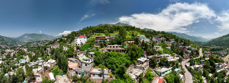 Aerial view of the hillside city of Muzaffarabad featuring dense residential housing lush green trees winding roads and mountainous terrain in Muzaffarabad Azad Kashmir Pakistan. Aerial view of the hillside city of Muzaffarabad featuring dense residential housing lush green trees winding roads and mountainous terrain in Muzaffarabad Azad Kashmir Pakistan.
