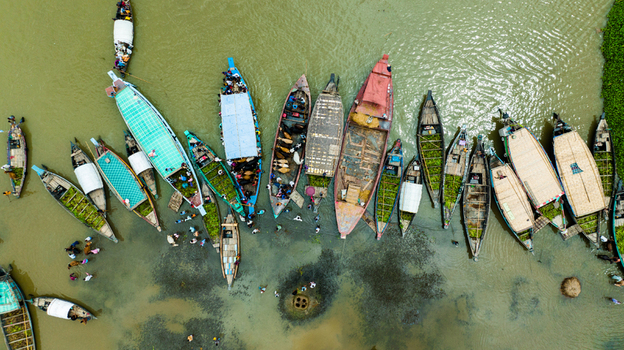 Aerial view of Baish Mowza Sarak Bazar featuring numerous wooden boats carrying goods and people along the river in Nabinagar Chittagong Division Bangladesh. Aerial view of Baish Mowza Sarak Bazar featuring numerous wooden boats carrying goods and people along the river in Nabinagar Chittagong Division Bangladesh.