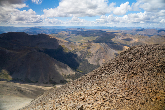 View of the rugged landscape near San Luis Peak and West Willow Creek Trailhead with rocky slopes distant mountain ranges and a cloudy blue sky in Creede Colorado United States. View of the rugged landscape near San Luis Peak and West Willow Creek Trailhead with rocky slopes distant mountain ranges and a cloudy blue sky in Creede Colorado United States.
