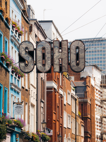 London United Kingdom 20 June 2025 View of the iconic Soho sign hanging above a street lined with colorful buildings a blend of brick and painted facades. London United Kingdom 20 June 2025 View of the iconic Soho sign hanging above a street lined with colorful buildings a blend of brick and painted facades.