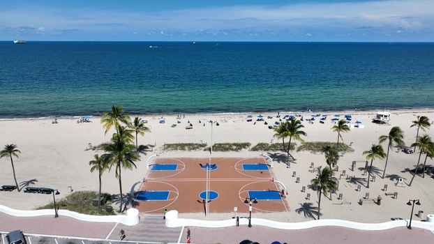 Aerial view of a vibrant basketball court on the sandy beach contrasting with the deep blue ocean Fort Lauderdale Florida United States.