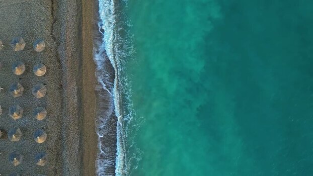 Aerial view of beach umbrellas along the turquoise coast Greece.