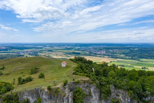 Aerial view of the Walberla hill with the St. Walburga chapel atop rocky cliffs overlooking the green fields of Franconian Switzerland in Kirchehrenbach Bavaria Germany. Aerial view of the Walberla hill with the St. Walburga chapel atop rocky cliffs overlooking the green fields of Franconian Switzerland in Kirchehrenbach Bavaria Germany.