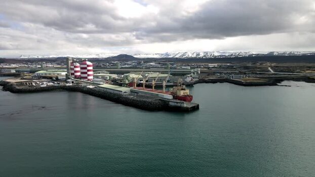 Aerial view of an industrial port with a cargo ship and striped silos Iceland.