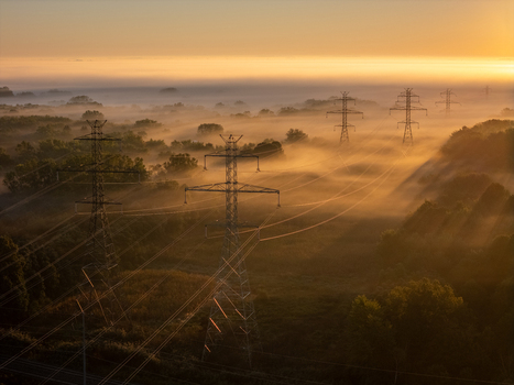 Aerial view of transmission lines and towers rising above a dense layer of morning fog at sunrise in a rural landscape in Bridgman Michigan United States.