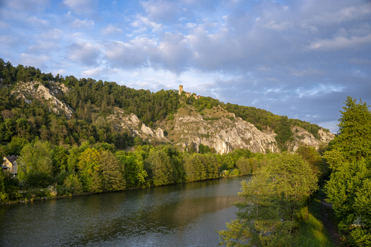 View of Randeck Castle perched on a rocky limestone hill above the Altmuhl river surrounded by dense green forest Essing Bayern Germany.