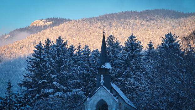 Aerial view of the church of Vesancy spire surrounded by snow covered pine trees and majestic mountains during winter Vesancy Auvergne Rhone Alpes France. Aerial view of the church of Vesancy spire surrounded by snow covered pine trees and majestic mountains during winter Vesancy Auvergne Rhone Alpes France.