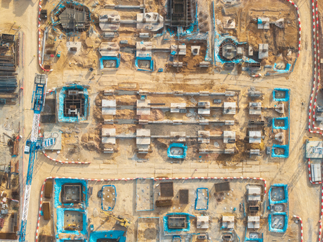 Aerial view of a construction site with concrete foundations blue protective sheeting and a crane in Bukit Tambun Penang Malaysia. Aerial view of a construction site with concrete foundations blue protective sheeting and a crane in Bukit Tambun Penang Malaysia.