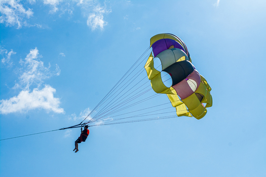 Cox s Bazar Bangladesh 18 August 2023 Aerial view of a vibrant yellow purple black and white parasail gracefully soaring under a clear blue sky. Cox s Bazar Bangladesh 18 August 2023 Aerial view of a vibrant yellow purple black and white parasail gracefully soaring under a clear blue sky.