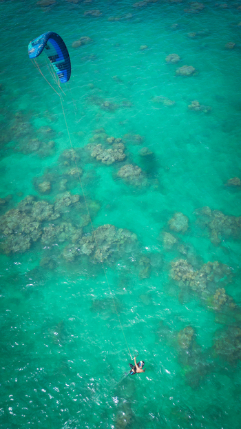 Aerial view of a kite surfer gliding over the vibrant turquoise waters and coral reefs near Lanikai Beach Kailua Hawaii United States. Aerial view of a kite surfer gliding over the vibrant turquoise waters and coral reefs near Lanikai Beach Kailua Hawaii United States.