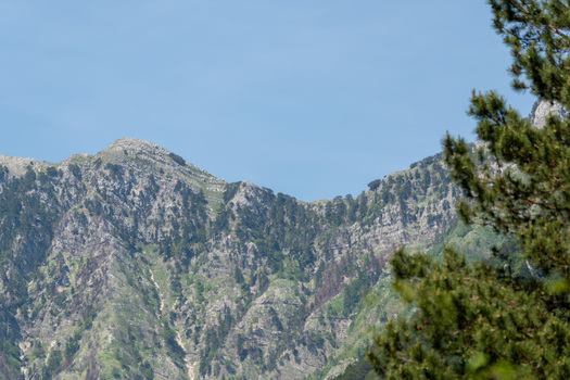View of the rocky mountain peaks of Panorama Llogora with sparse green vegetation under a clear blue sky Himare Qarku i Vlores Albania.