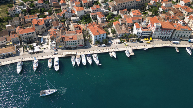 Aerial view of the historic waterfront with red roofed stone buildings and yachts moored in the turquoise harbor in Vis Split Dalmatia County Croatia. Aerial view of the historic waterfront with red roofed stone buildings and yachts moored in the turquoise harbor in Vis Split Dalmatia County Croatia.