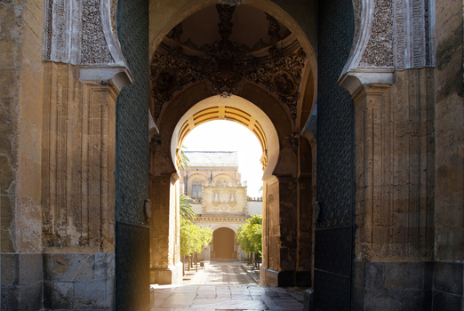 Cordoba Spain 04 September 2026 View of the Mosque Cathedral Monumental Site of Cordoba featuring an ornate horseshoe archway leading to a sunlit courtyard with orange trees.
