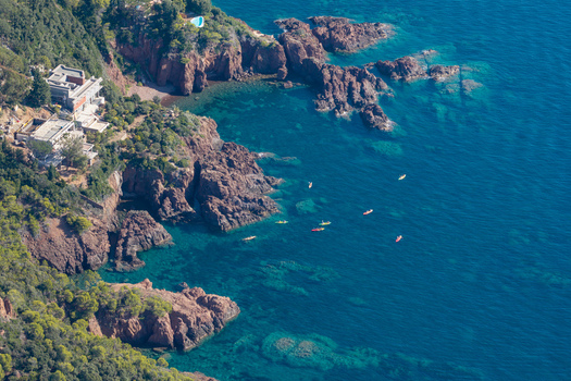Aerial view of Le Trayas featuring rugged red rock cliffs meeting the Mediterranean Sea with colorful kayaks paddling in the water near Saint Raphael Provence Alpes Cote d Azur France. Aerial view of Le Trayas featuring rugged red rock cliffs meeting the Mediterranean Sea with colorful kayaks paddling in the water near Saint Raphael Provence Alpes Cote d Azur France.
