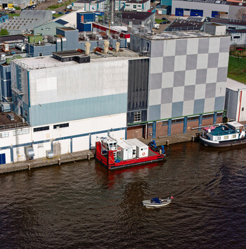 Wormer Netherlands 10 April 2026 Aerial view of a vibrant red and white electric pusher tug moored beside the Olam International Cacoa factory contrasting with the dark waters. Wormer Netherlands 10 April 2026 Aerial view of a vibrant red and white electric pusher tug moored beside the Olam International Cacoa factory contrasting with the dark waters.