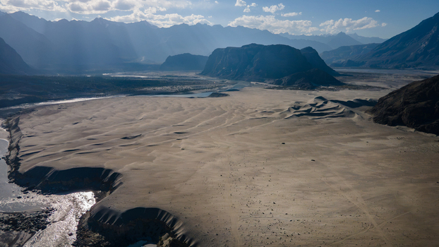 Aerial view of Sarfaranga Cold Desert Shigar with vast sand dunes a winding river and dramatic mountain peaks in Skardu Gilgit Pakistan.