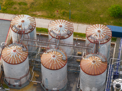 Aerial view of six large industrial storage tanks with rusty conical roofs and connecting metal walkways in Breclav South Moravian Region Czechia.