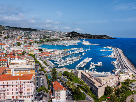 Aerial view of the harbor and coastal skyline with colorful buildings and numerous boats docked in the marina under a clear blue sky in Sanremo Liguria Italy. Aerial view of the harbor and coastal skyline with colorful buildings and numerous boats docked in the marina under a clear blue sky in Sanremo Liguria Italy.