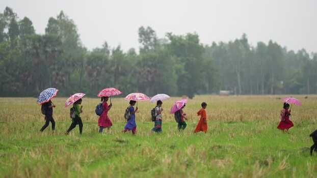 View of children walking with umbrellas in a field Bangladesh.