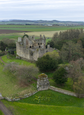 Aerial view of the historic ruins of Dirleton Castle and Gardens with stone walls and lush greenery in Dirleton Scotland United Kingdom. Aerial view of the historic ruins of Dirleton Castle and Gardens with stone walls and lush greenery in Dirleton Scotland United Kingdom.