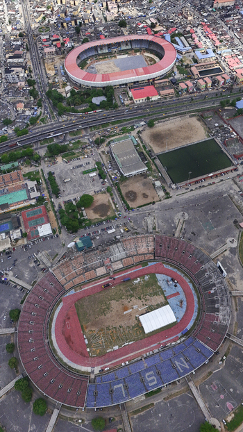 Aerial view of the National Stadium Surulere Lagos and Teslim Balogun Stadium surrounded by urban infrastructure and dense residential areas in Lagos Lagos Nigeria. Aerial view of the National Stadium Surulere Lagos and Teslim Balogun Stadium surrounded by urban infrastructure and dense residential areas in Lagos Lagos Nigeria.