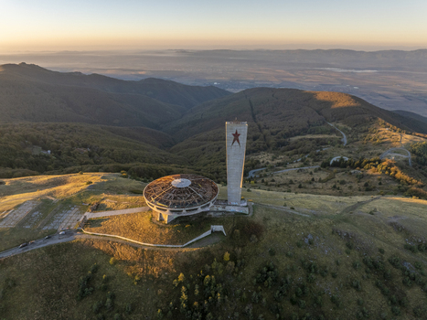 Aerial view of the iconic Buzludzha Monument featuring its saucer shaped structure and tower with a red star situated atop a mountain peak during golden hour in Stara Zagora Bulgaria. Aerial view of the iconic Buzludzha Monument featuring its saucer shaped structure and tower with a red star situated atop a mountain peak during golden hour in Stara Zagora Bulgaria.