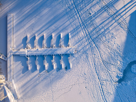 Aerial view of a snow covered wooden pier on a frozen lake with long shadows and footprints in Trakai Vilnius County Lithuania. Aerial view of a snow covered wooden pier on a frozen lake with long shadows and footprints in Trakai Vilnius County Lithuania.