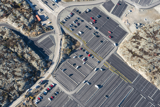Aerial view of Tuvesvik ferry terminal parking lot with cars parked in rows surrounded by rocky terrain in Ellos Vastra Gotaland County Sweden.