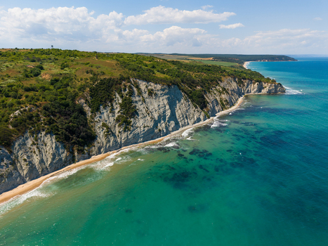 Aerial view of the White Cliffs of Byala featuring dramatic limestone rock formations lush green vegetation and turquoise coastal waters under a clear blue sky in Byala Varna Bulgaria. Aerial view of the White Cliffs of Byala featuring dramatic limestone rock formations lush green vegetation and turquoise coastal waters under a clear blue sky in Byala Varna Bulgaria.