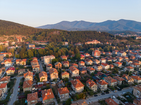 Aerial view of the town of Velingrad with residential houses lush green trees and mountains in the background in Velingrad Pazardzhik Bulgaria. Aerial view of the town of Velingrad with residential houses lush green trees and mountains in the background in Velingrad Pazardzhik Bulgaria.