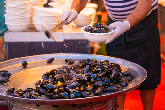 View of a chef serving steaming mussels from a large metal dish a culinary symphony of colors and aromas in Pula Istria County Croatia.