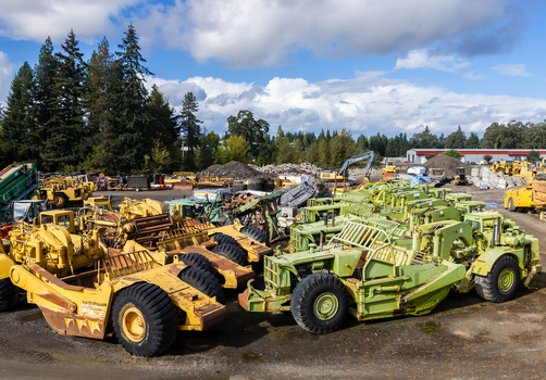 Woodburn United States 25 September 2026 Aerial view of heavy construction machinery including yellow and green scrapers parked in an industrial yard surrounded by trees under a cloudy sky. Woodburn United States 25 September 2026 Aerial view of heavy construction machinery including yellow and green scrapers parked in an industrial yard surrounded by trees under a cloudy sky.