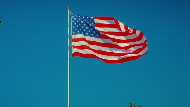 View of the American flag against a blue sky United States. View of the American flag against a blue sky United States.