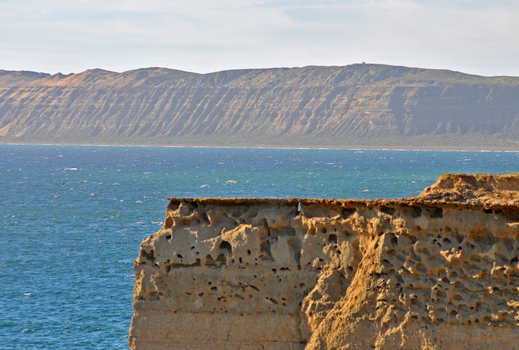 View of the eroded sandstone cliffs of Puerto Piramides overlooking the blue waters of the Atlantic Ocean in Puerto Madryn Chubut Argentina. View of the eroded sandstone cliffs of Puerto Piramides overlooking the blue waters of the Atlantic Ocean in Puerto Madryn Chubut Argentina.