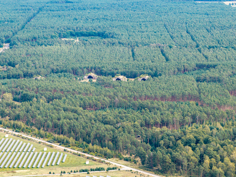 Aerial view of the solar farm at the former Preschen military airfield featuring historic hardened aircraft shelters nestled within a pine forest in Neisse Malxetal Brandenburg Germany. Aerial view of the solar farm at the former Preschen military airfield featuring historic hardened aircraft shelters nestled within a pine forest in Neisse Malxetal Brandenburg Germany.