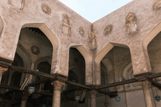 View of the Mosque of al Salih Tala i featuring historic stone arches decorative medallions and hanging lamps Cairo Egypt. View of the Mosque of al Salih Tala i featuring historic stone arches decorative medallions and hanging lamps Cairo Egypt.